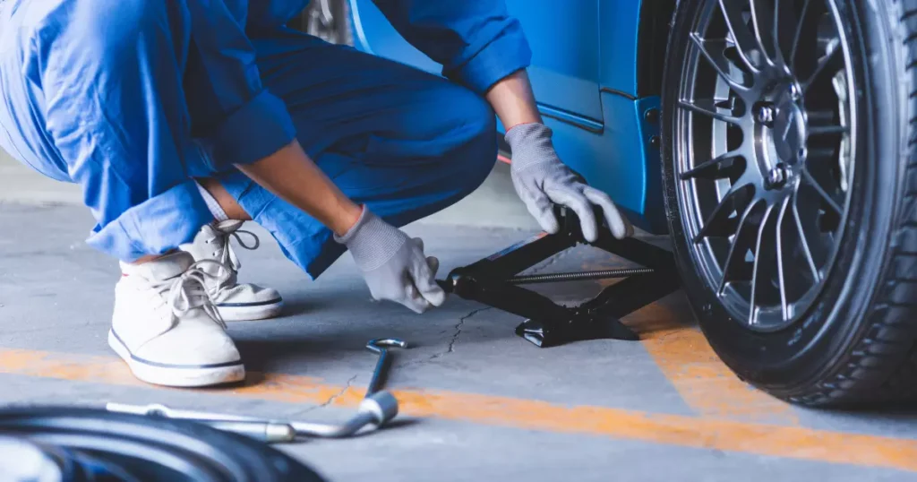 a mechanic in blue overalls working on a jack