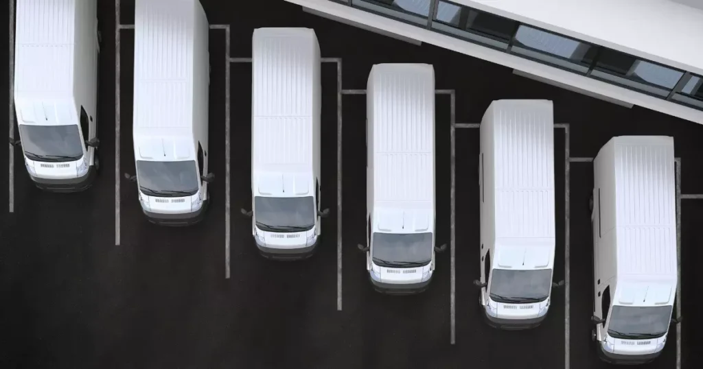 A top-down view of neatly parked white fleet vans outside a commercial building, emphasizing organized fleet car maintenance practices for operational efficiency.