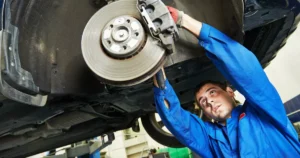 Mechanic working under a car, checking for signs of brake problems